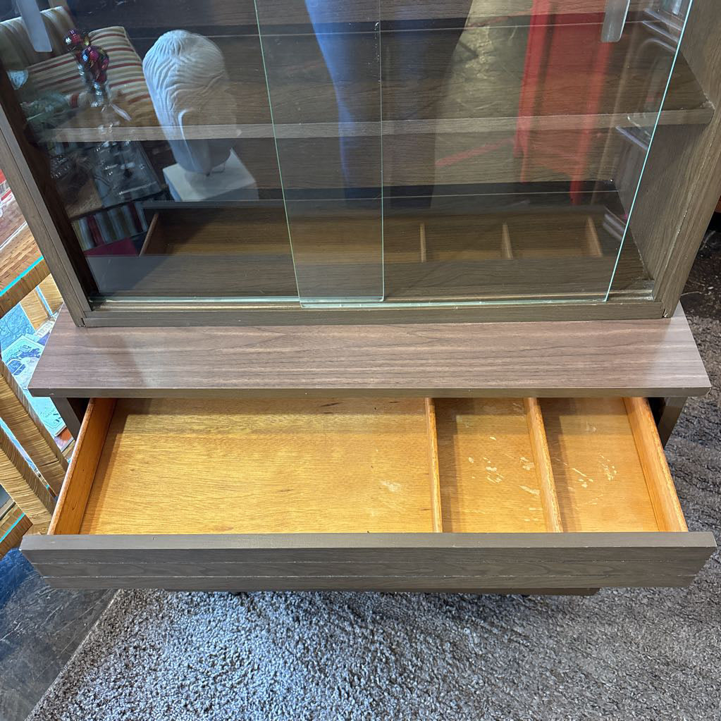 A large wooden hutch with two sliding wooden doors. The cabinet is in a store setting. 