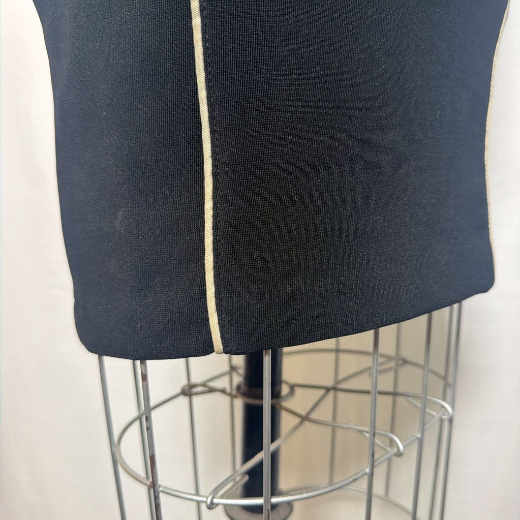A black pencil skirt with white lines down the front and side on an antique mannequin in front of a white fabric wall. 