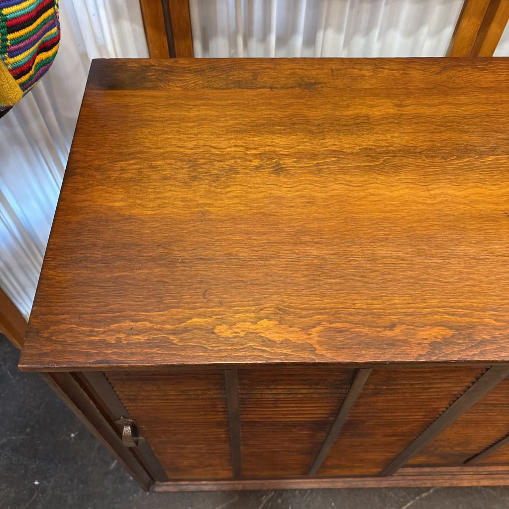 A brown wooden cabinet with sliding doors in a room setting.