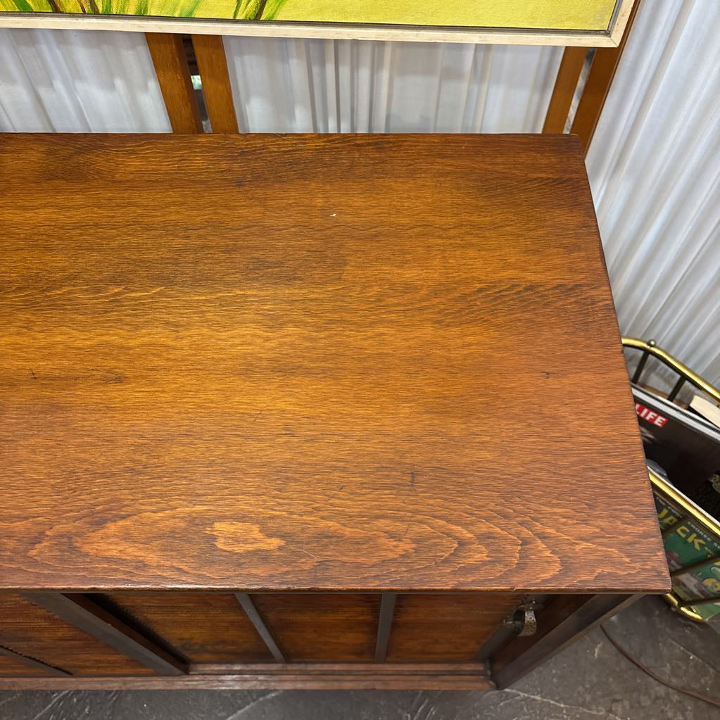 A close-up view of a medium brown wooden cabinet or desk top with visible wood grain, photographed in what appears to be a store or workshop setting.