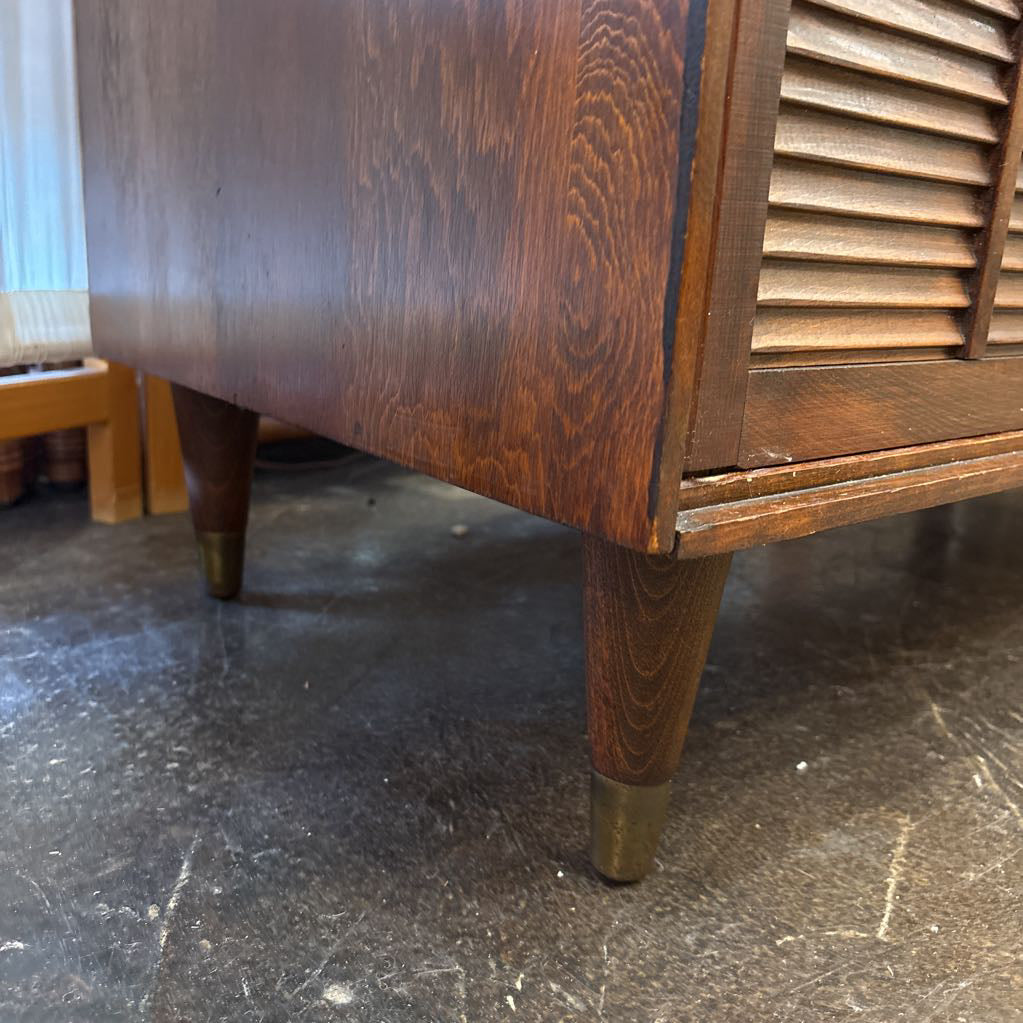 A brown wooden cabinet with sliding doors in a room setting.