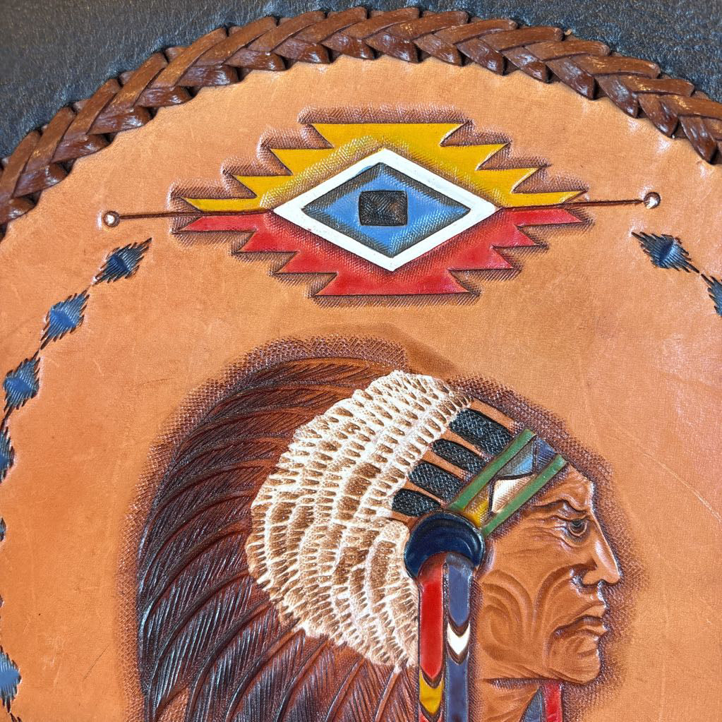 A black leather belt bag with a Native American figure's profile embossed in a circular design on the front. 