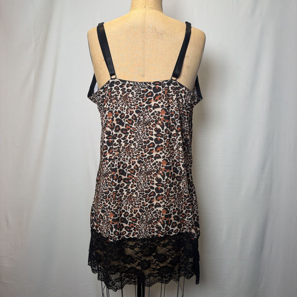 A leopard print lingerie slip dress with black lace trimmings on an antique style mannequin in front of a white fabric wall. 