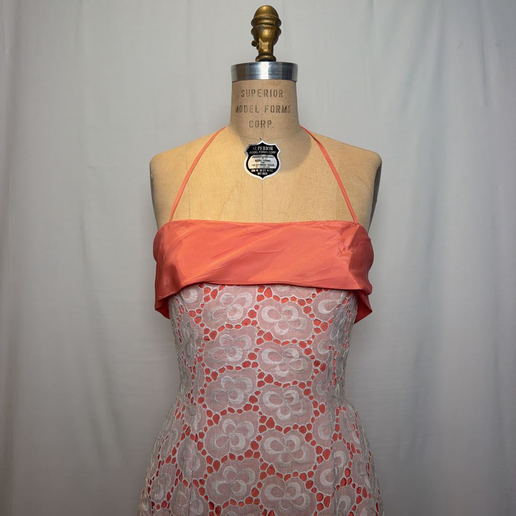 A peach and white lace halter mini dress on an antique style mannequin, against a white fabric wall. 