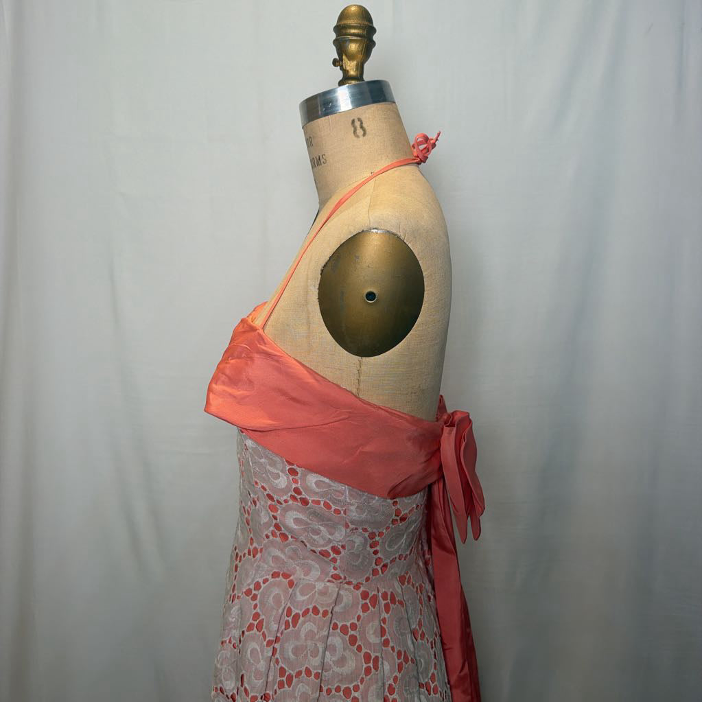 A peach and white lace halter mini dress on an antique style mannequin, against a white fabric wall. 
