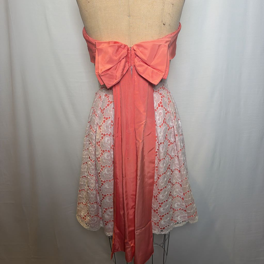A peach and white lace halter mini dress on an antique style mannequin, against a white fabric wall. 
