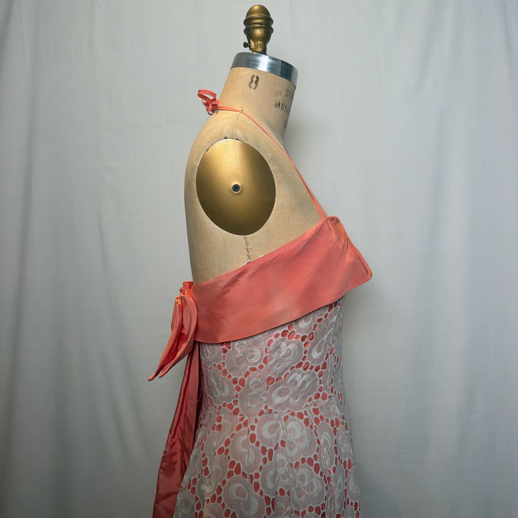 A peach and white lace halter mini dress on an antique style mannequin, against a white fabric wall. 