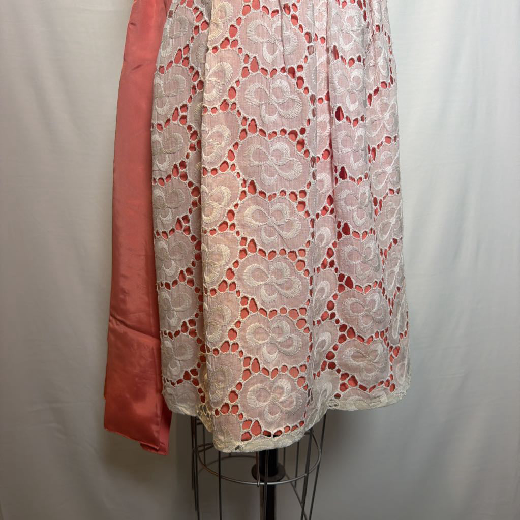 A peach and white lace halter mini dress on an antique style mannequin, against a white fabric wall. 
