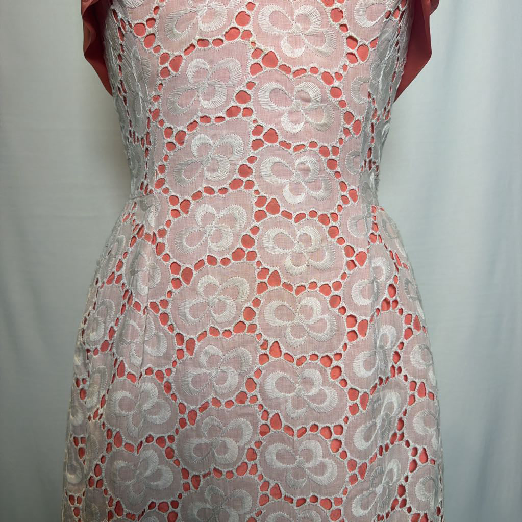A peach and white lace halter mini dress on an antique style mannequin, against a white fabric wall. 