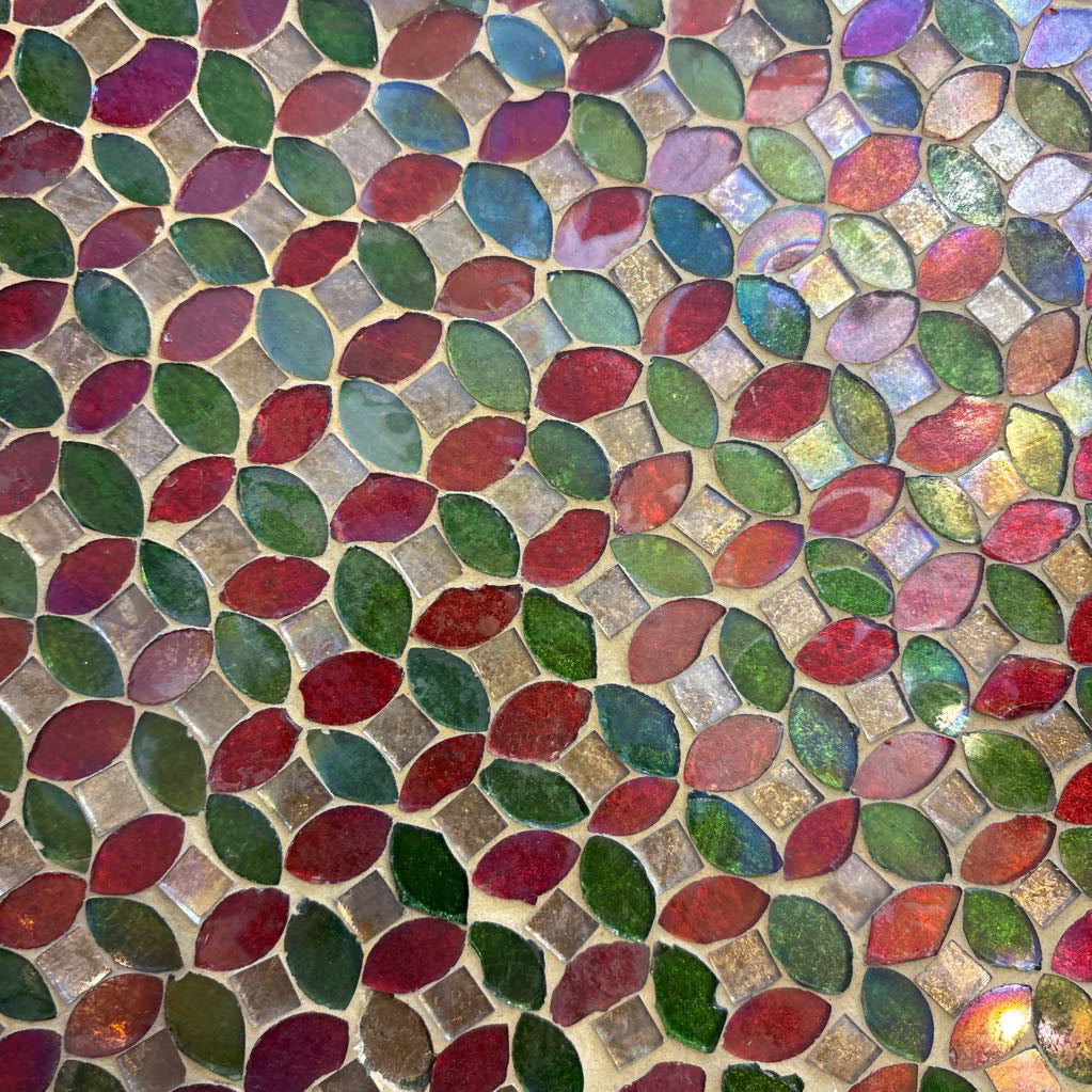 A large tray with a glass mosaic design on a brown rug. 