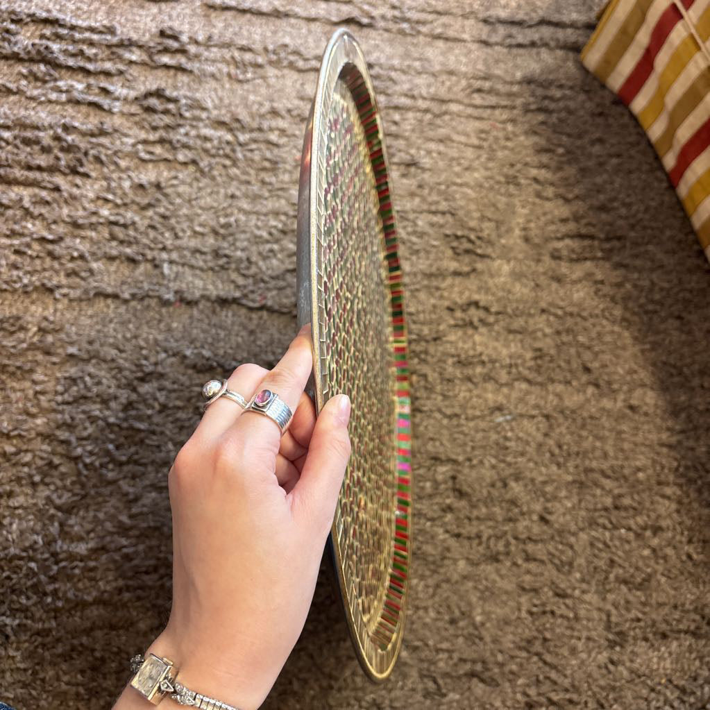A large tray with a glass mosaic design on a brown rug. 