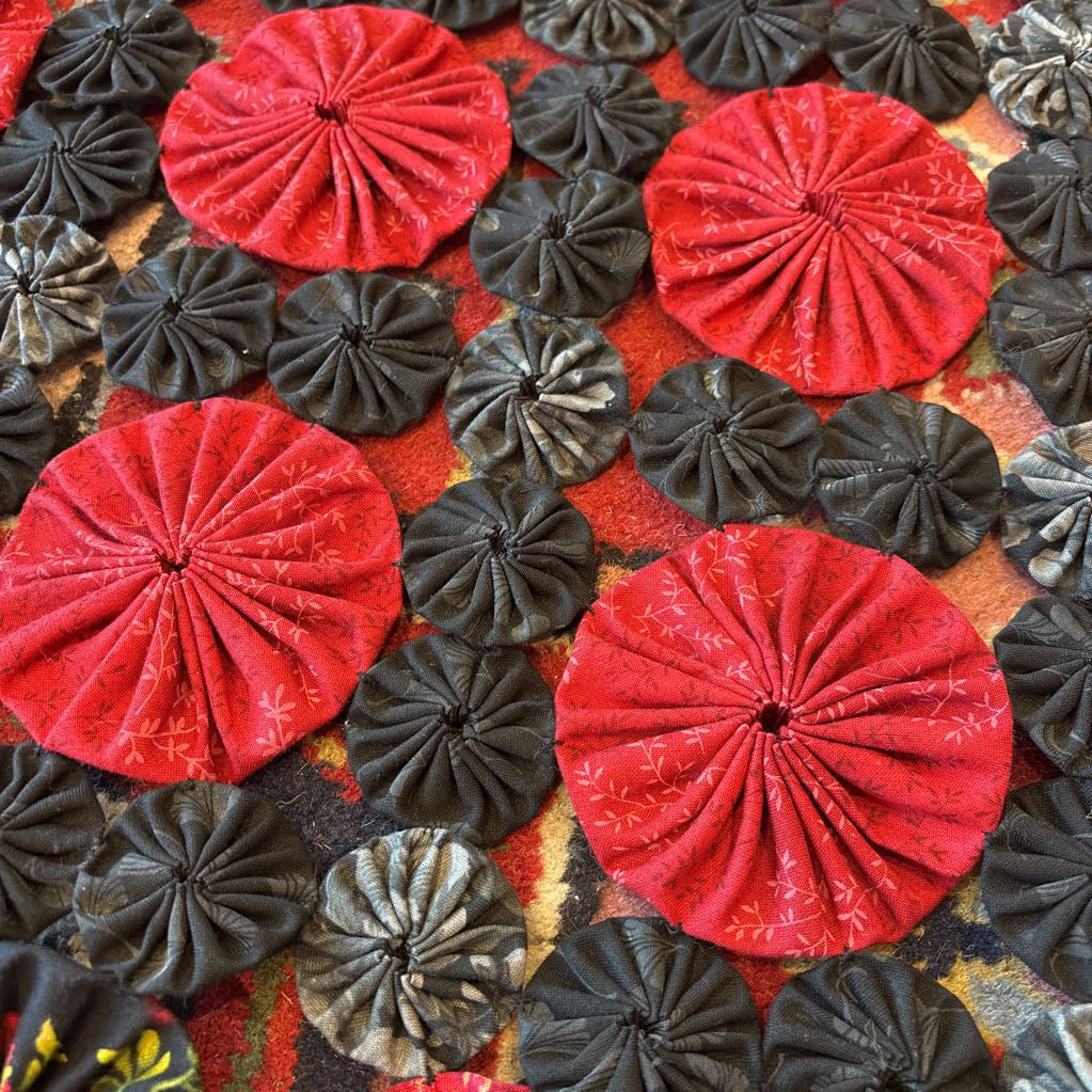 A red and black puff quilt on a red rug.
