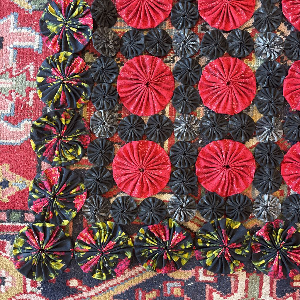 A red and black puff quilt on a red rug.