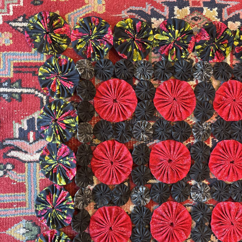 A red and black puff quilt on a red rug.