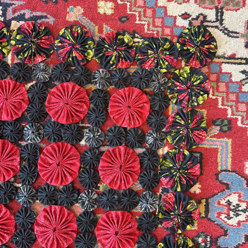 A red and black puff quilt on a red rug.