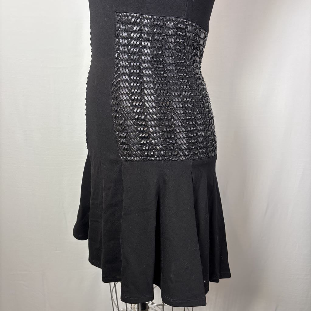 A black strapless dress displayed on a mannequin, featuring a structured, textured geometric patterned bodice panel and a flared skirt against a plain light background.