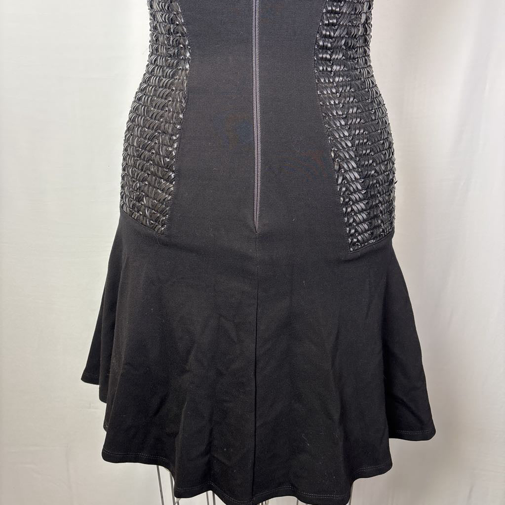 Black sleeveless dress with textured metallic mesh panels on the sides and a flared skirt, shown on a mannequin against a white backdrop.
