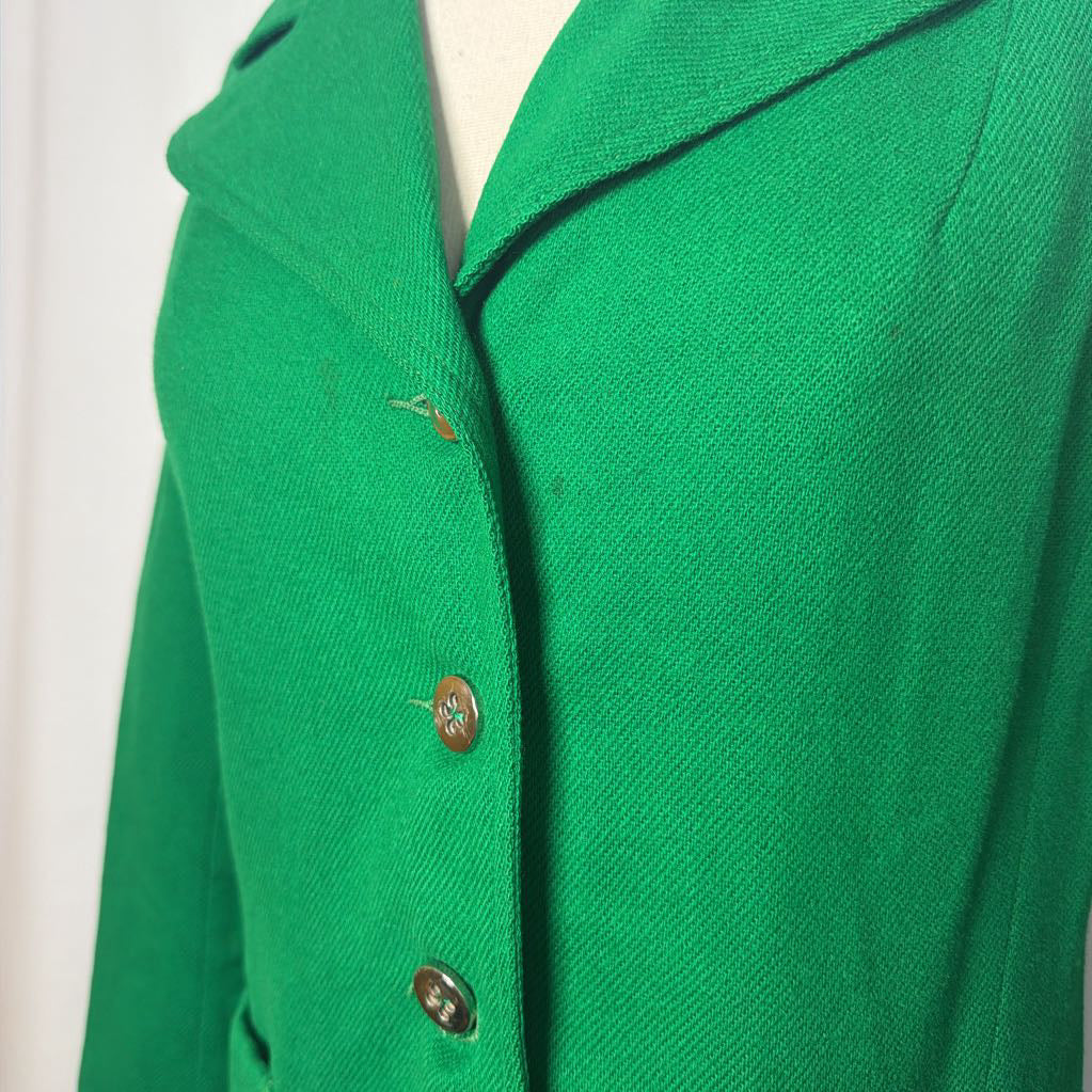 A close-up of a bright green textured jacket or cardigan with three brown buttons, shown on a white mannequin torso against a white background.