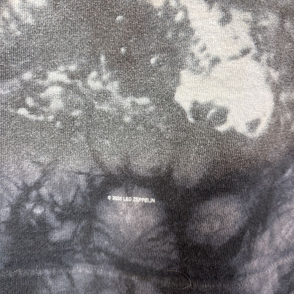 A dark gray tie-dye short sleeve t-shirt with an image of Led Zeppelin on it. The tee hangs on a wooden rack against a white background.
