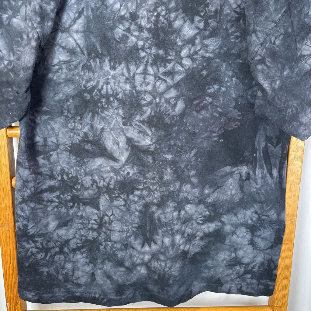A dark gray tie-dye short sleeve t-shirt on a wooden rack against a white background.