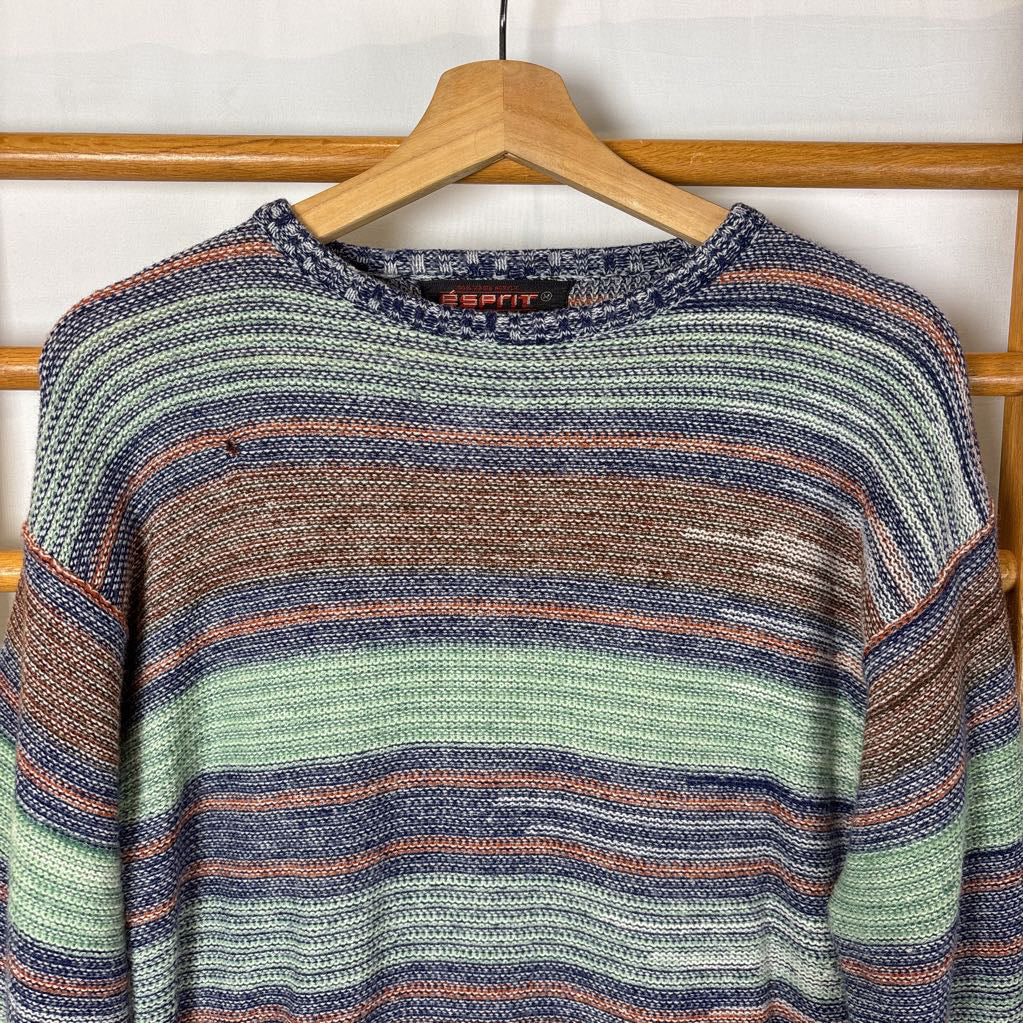 A blue, green, and brown striped knitted long sleeve sweater hanging on a wooden rack against a white background.