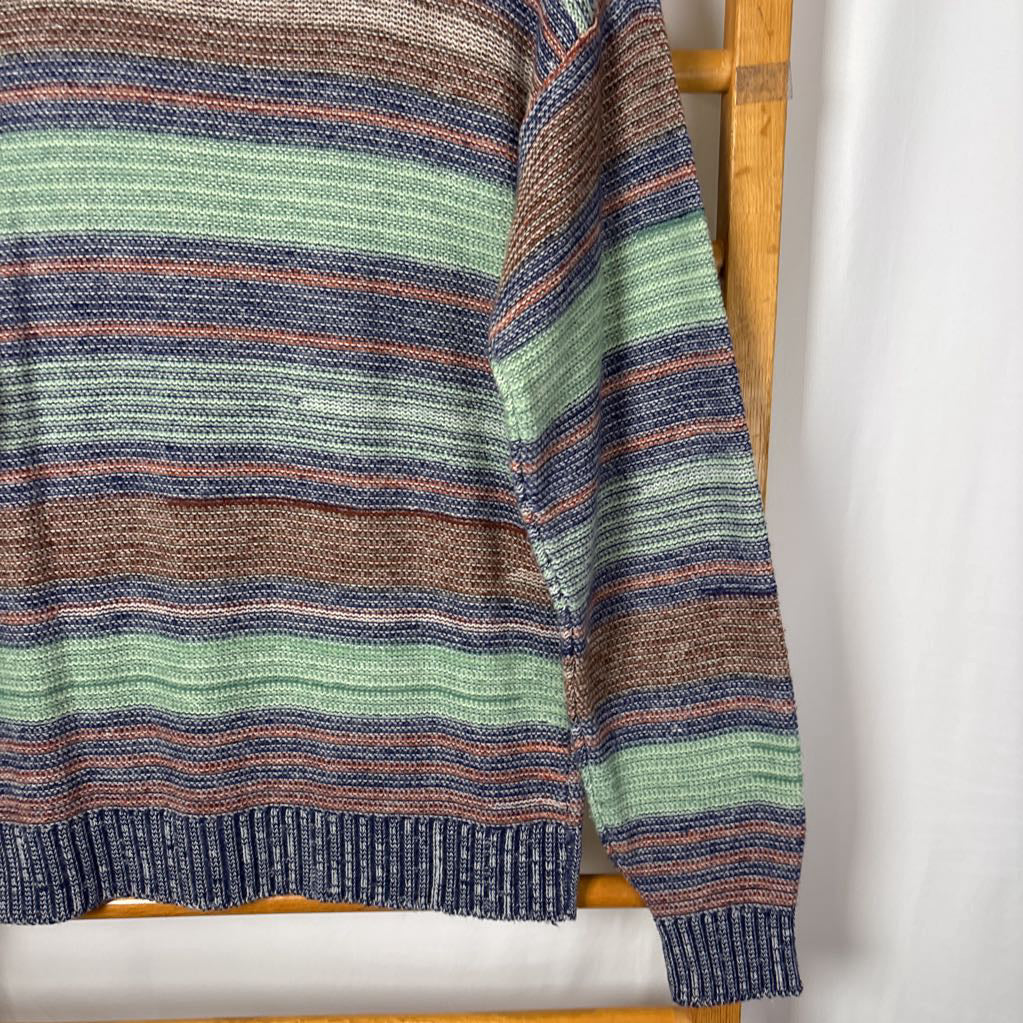 A blue, green, and brown striped knitted long sleeve sweater hanging on a wooden rack against a white background.