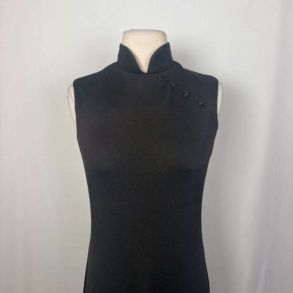 A black maxi dress with a butterfly and floral embroidery at the bottom. This dress is on a mannequin in front of a white wall. 