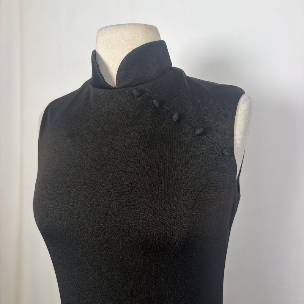 A black maxi dress with a butterfly and floral embroidery at the bottom. This dress is on a mannequin in front of a white wall. 