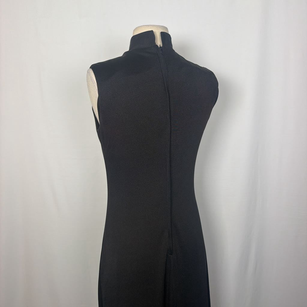 A black maxi dress with a butterfly and floral embroidery at the bottom. This dress is on a mannequin in front of a white wall. 