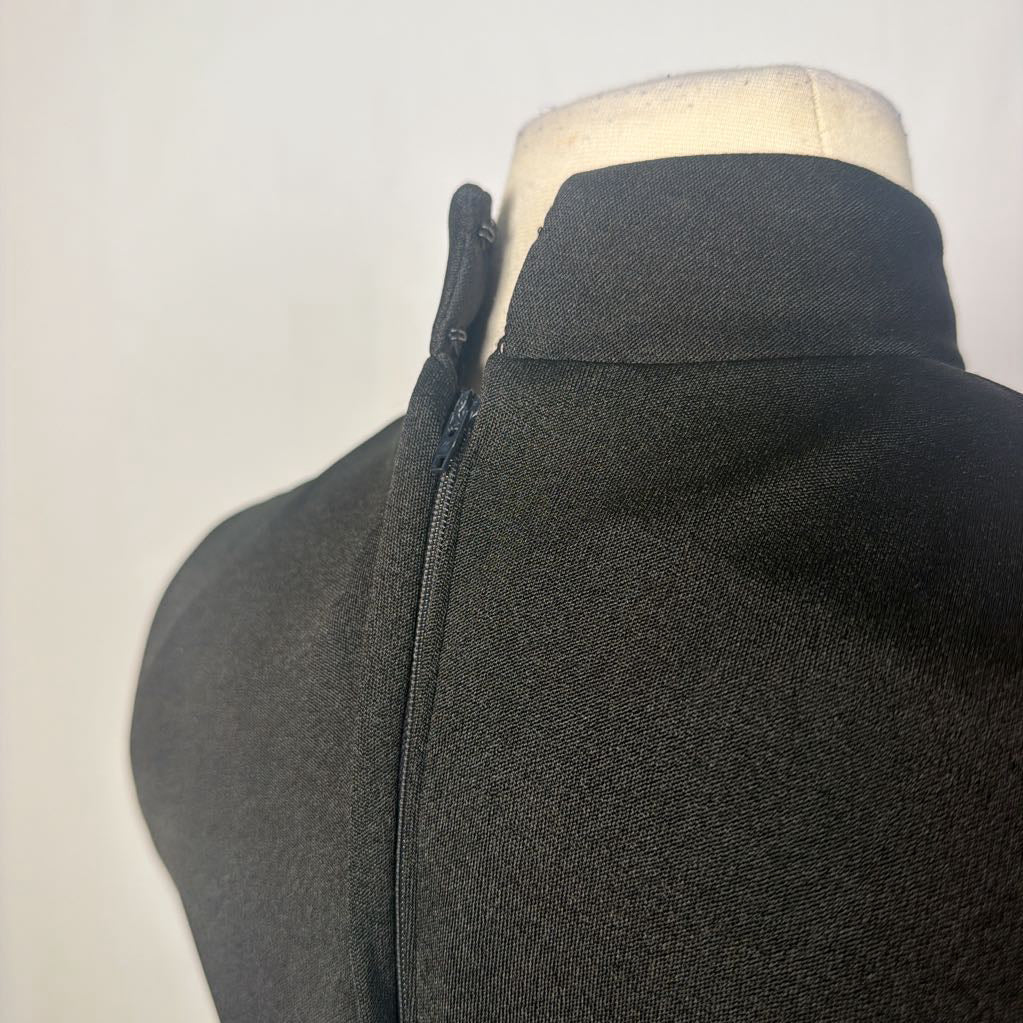 A black maxi dress with a butterfly and floral embroidery at the bottom. This dress is on a mannequin in front of a white wall. 