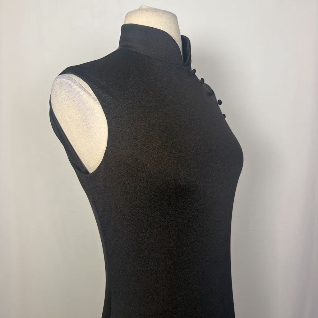 A black maxi dress with a butterfly and floral embroidery at the bottom. This dress is on a mannequin in front of a white wall. 