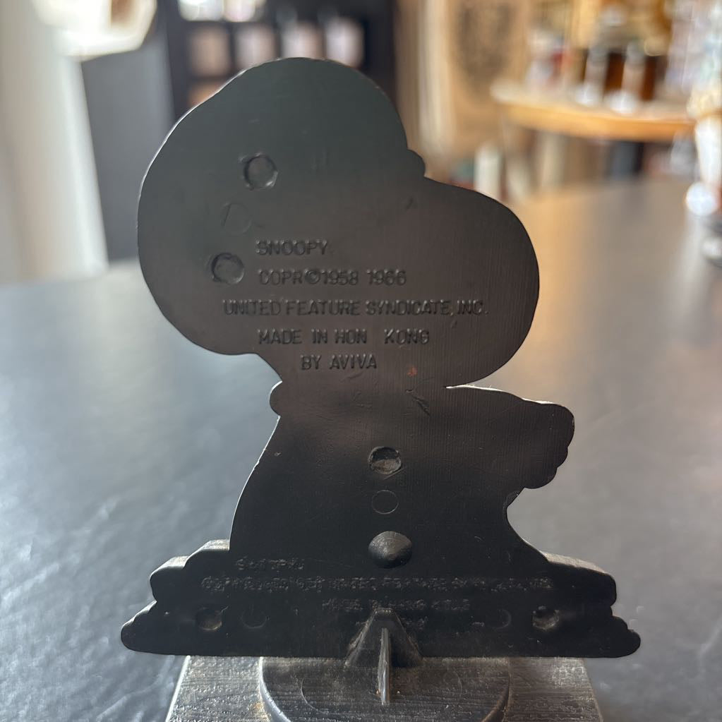 A small figure of snoopy on a pedestal. He's opening up a brown bag and the phrase at the bottom reads, "Life is like a brown bag...full of wonderful surprises!" 
