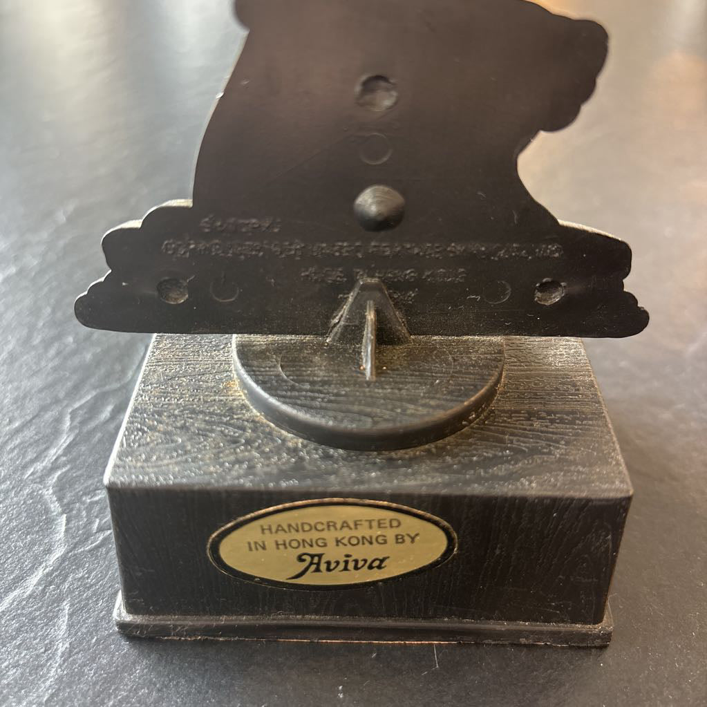 A small figure of snoopy on a pedestal. He's opening up a brown bag and the phrase at the bottom reads, "Life is like a brown bag...full of wonderful surprises!" 