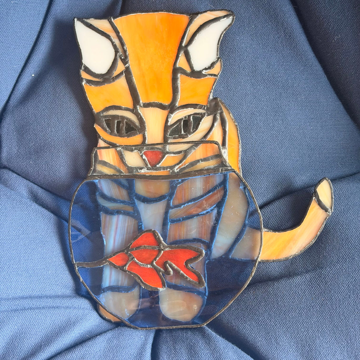 cat stained glass lookign at fish bowl 