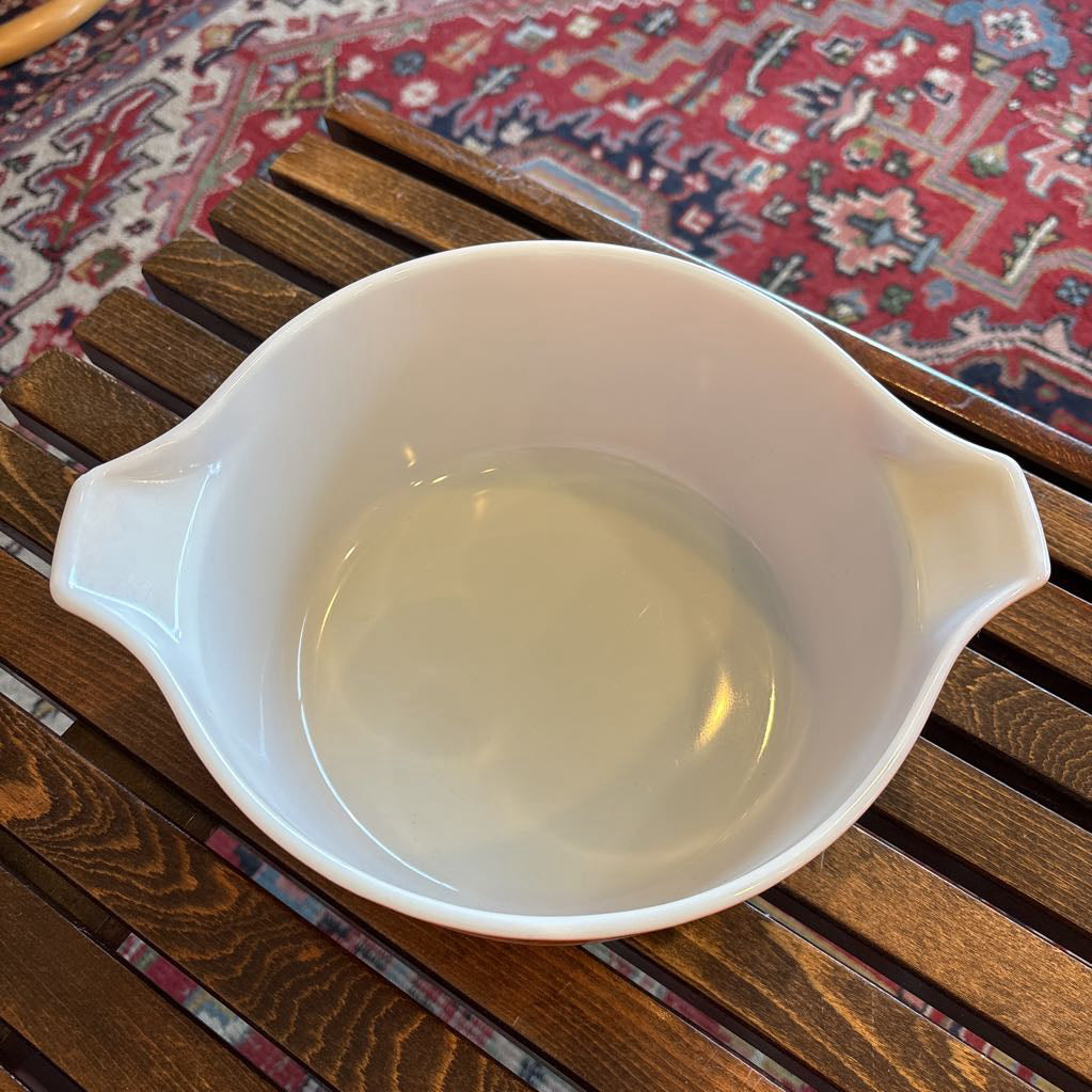 A casserole dish sitting on a wooden slat bench in a room setting. 