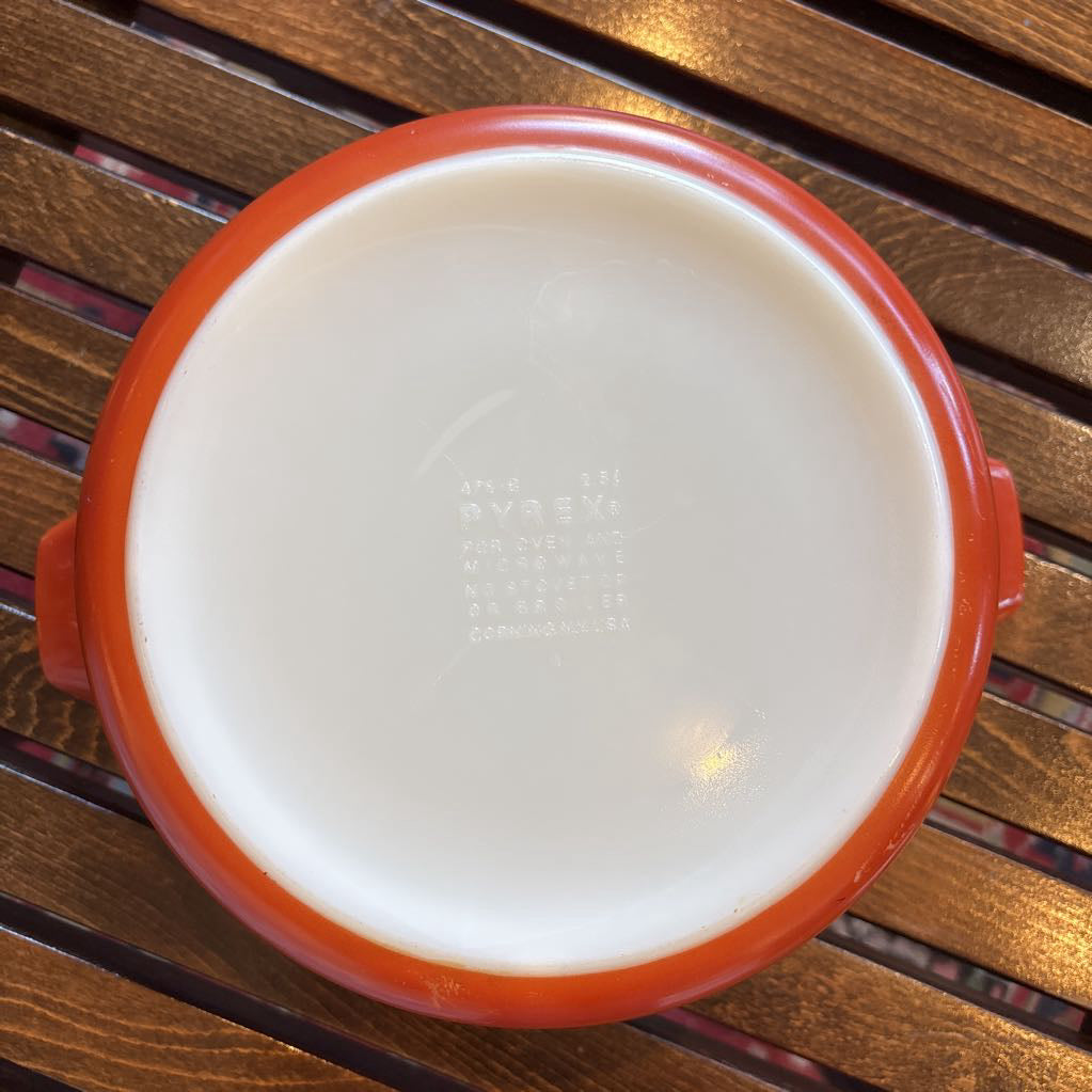 The bottom of a casserole dish on a wooden slat bench in a room setting. 