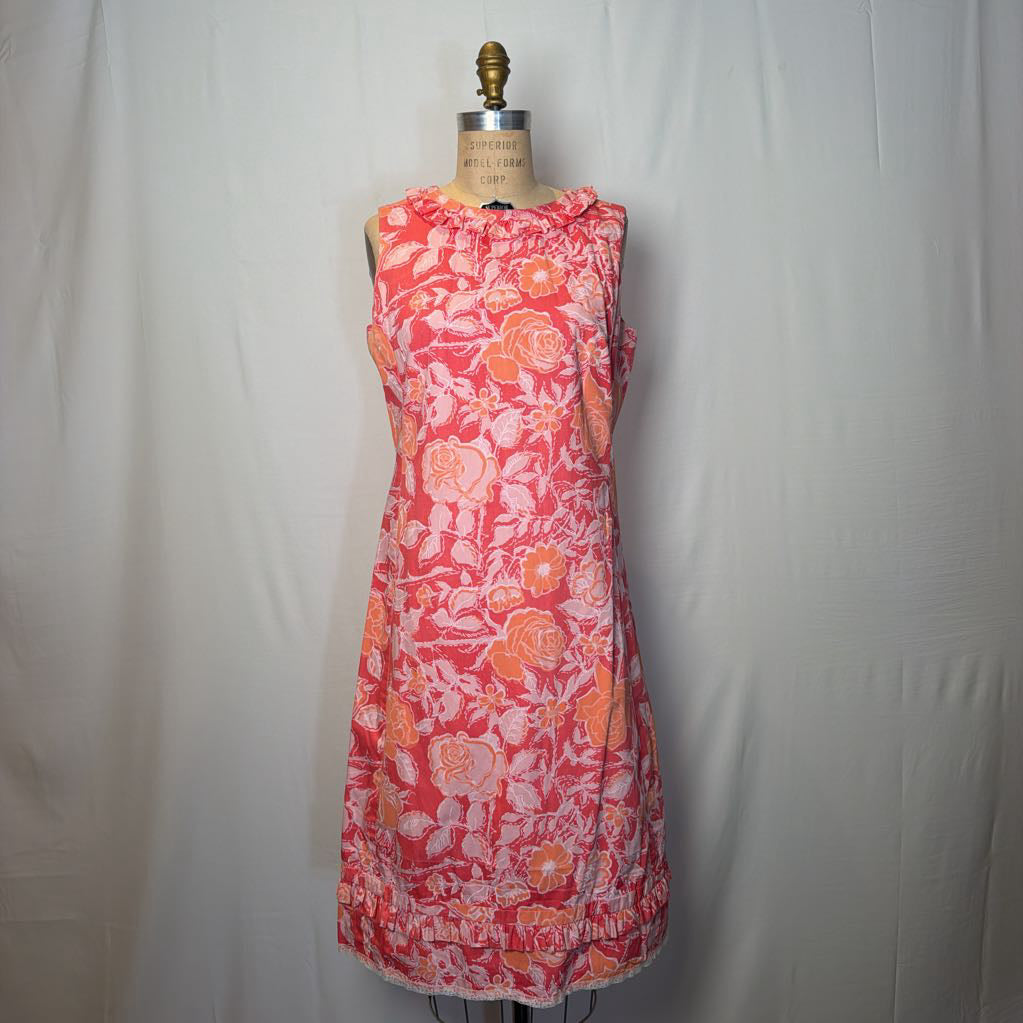 A pink & peach floral mod dress on a dress form in front of a white wall.