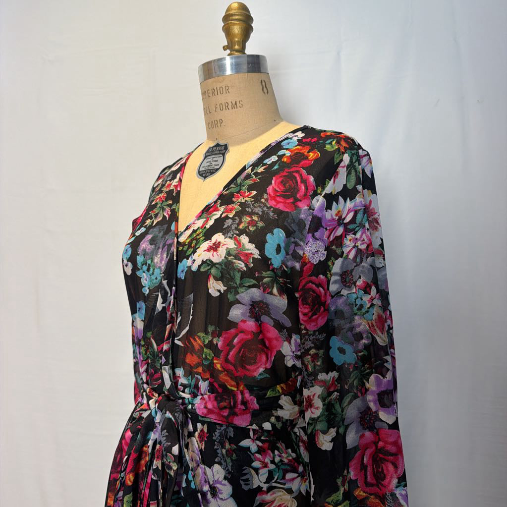 A floral maxi dress on a mannequin in front of a white wall. 