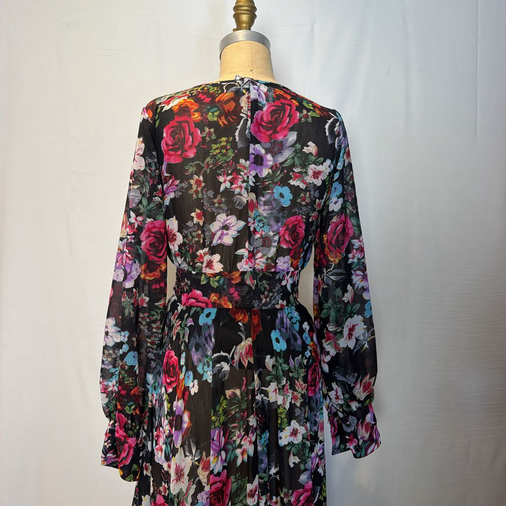 A floral maxi dress on a mannequin in front of a white wall. 
