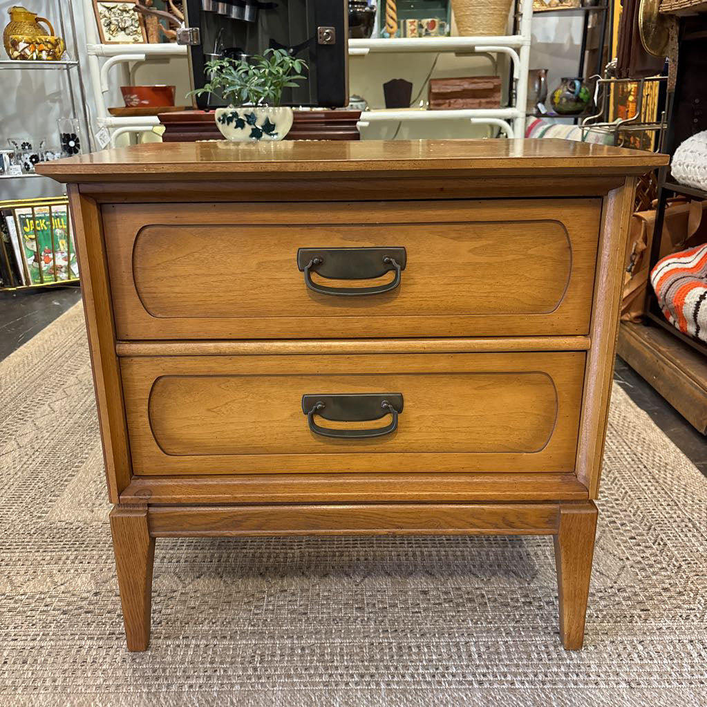 A wooden nightstand with drawers in a store setting. 