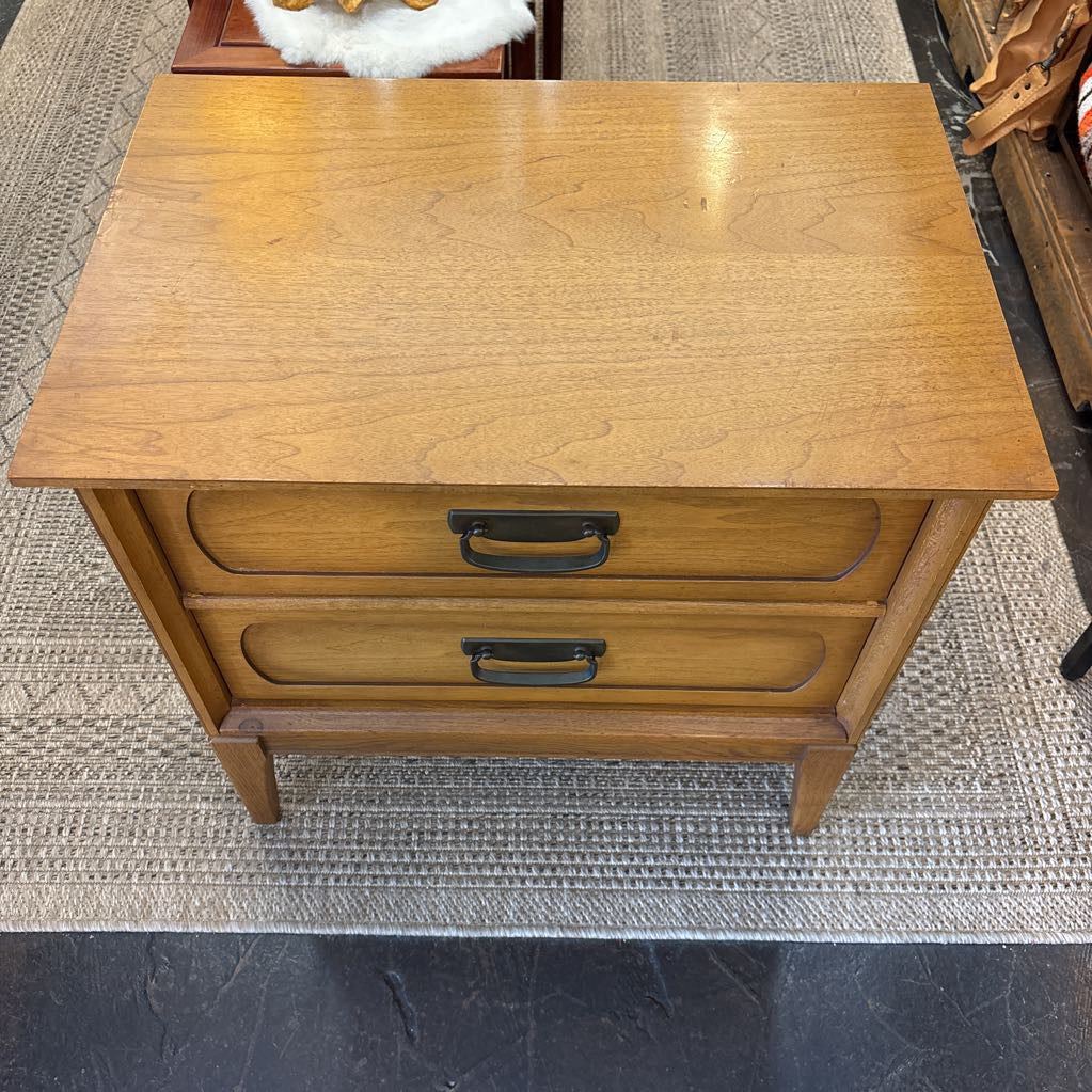 A wooden nightstand with drawers in a store setting. 