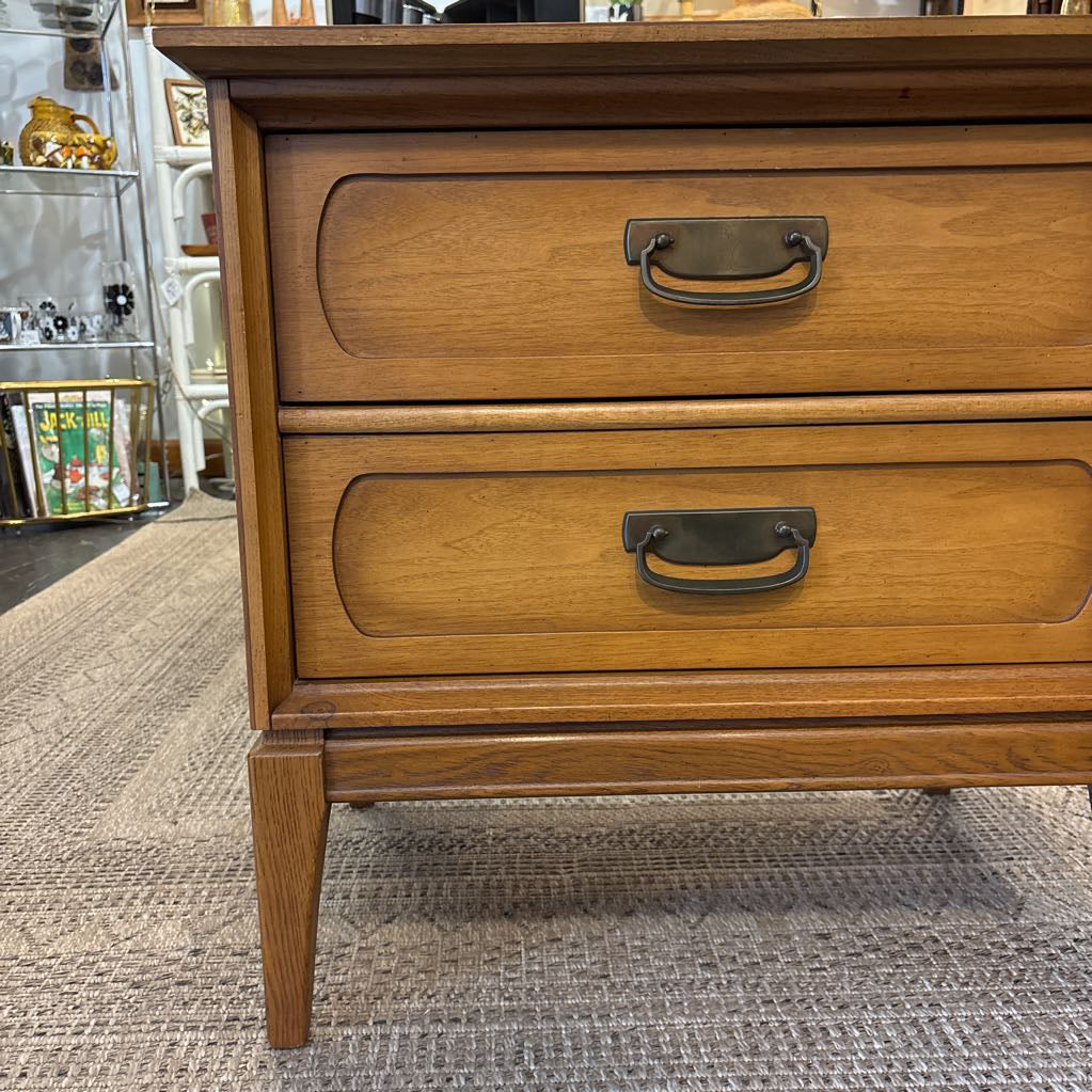 A wooden nightstand with drawers in a store setting. 