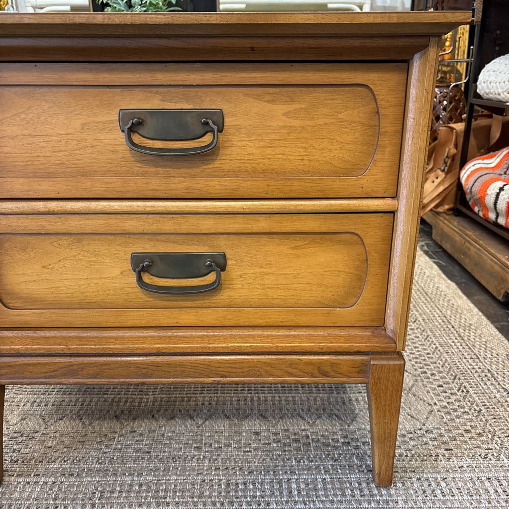 A wooden nightstand with drawers in a store setting. 
