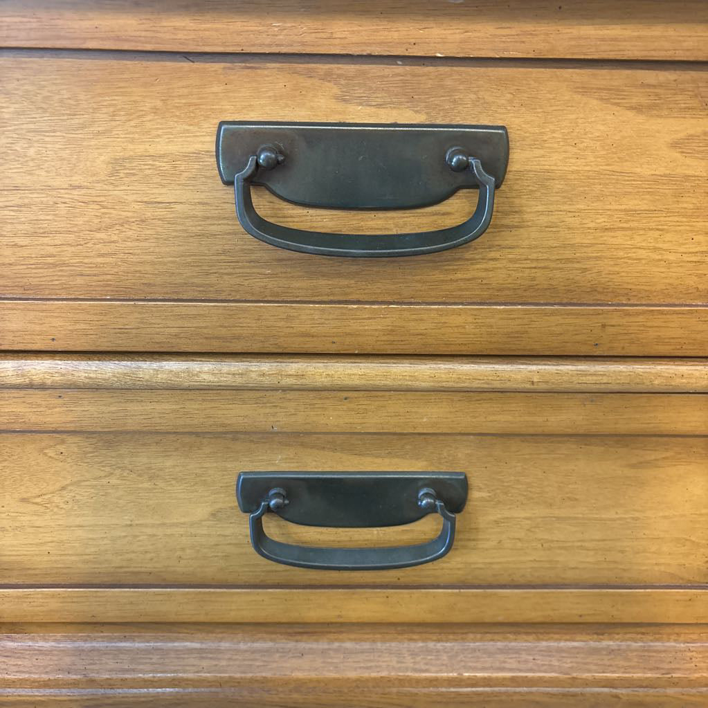 A wooden nightstand with drawers in a store setting. 