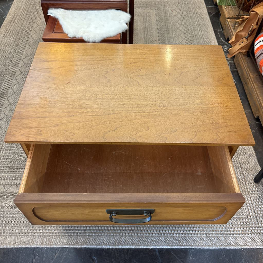A wooden nightstand with drawers in a store setting. 
