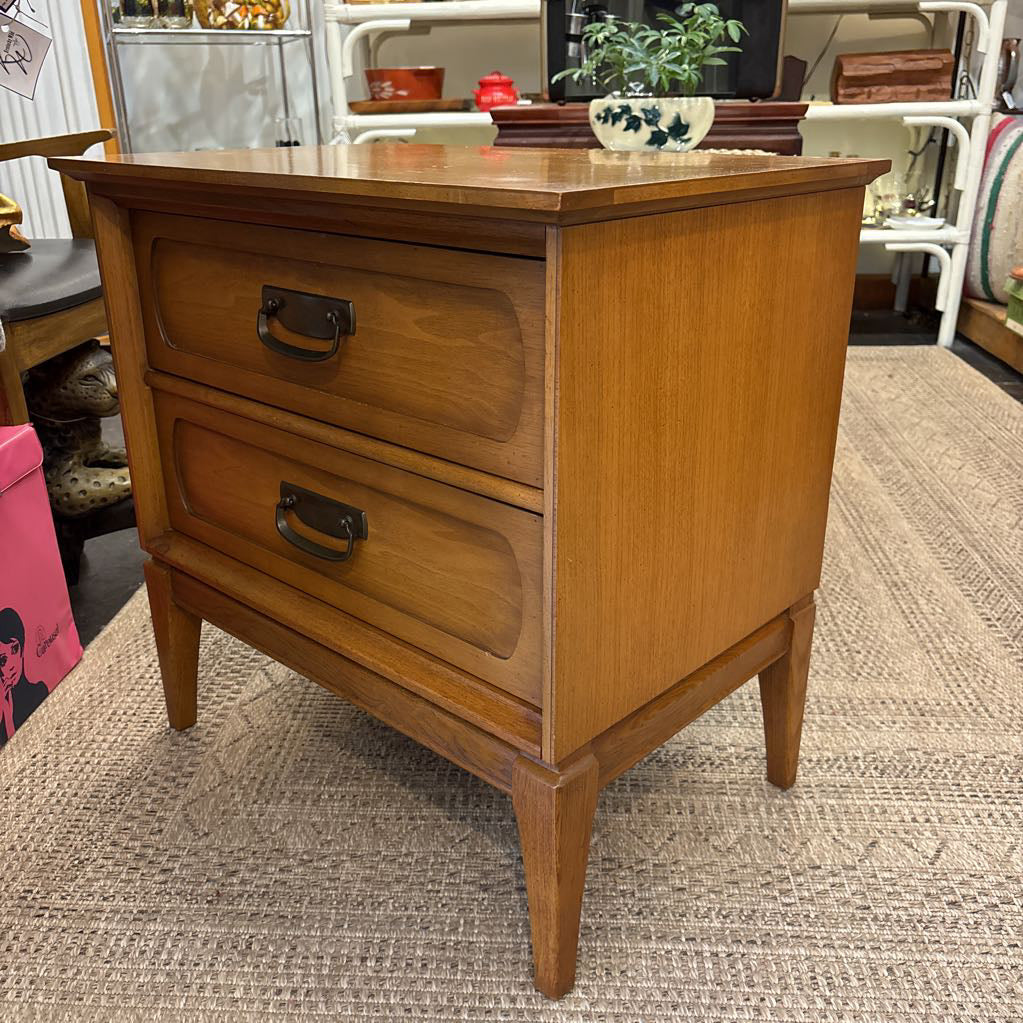 A wooden nightstand with drawers in a store setting. 