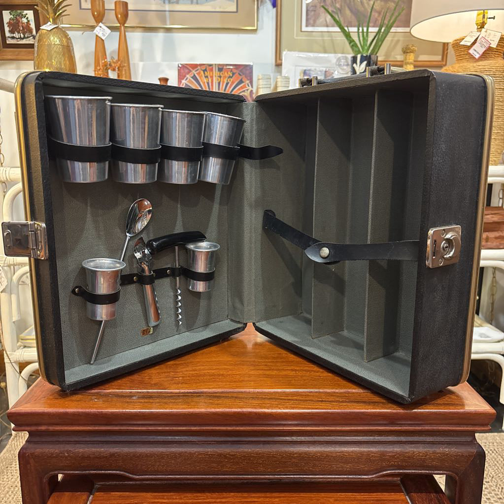 An open travel bar with multiple tools sitting on a wooden table in a room setting.