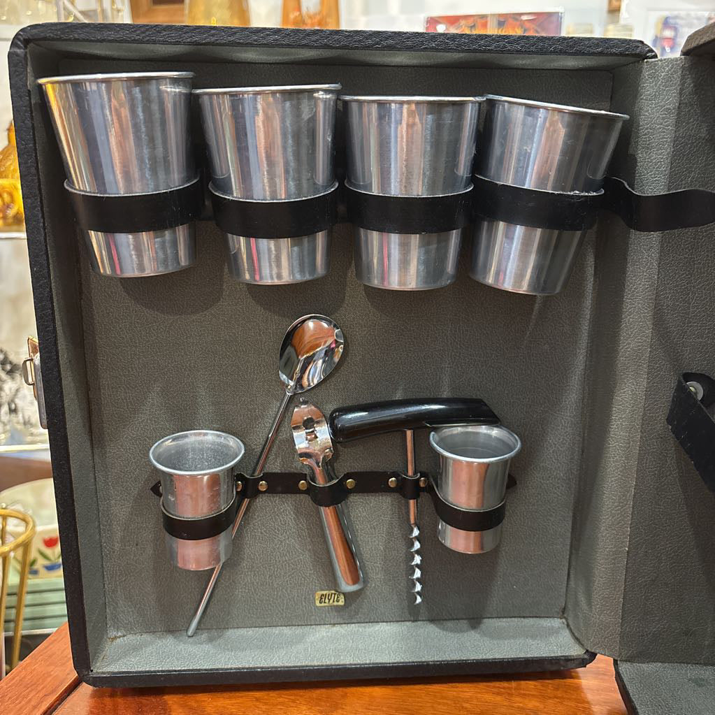 An open travel bar with multiple tools sitting on a wooden table in a room setting.