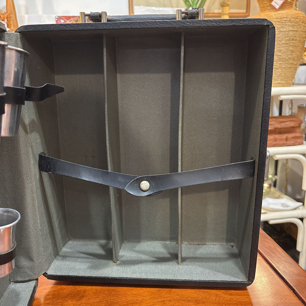 An open travel bar with multiple tools sitting on a wooden table in a room setting.