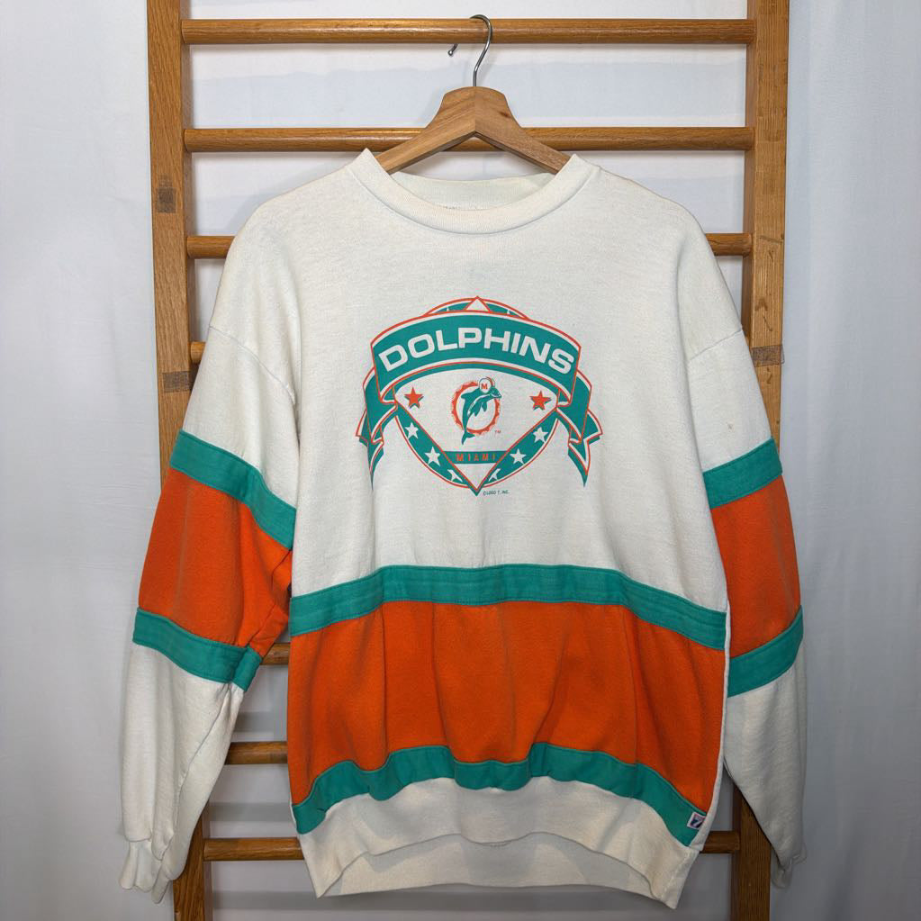 A white, orange, and turquoise Miami Dolphins branded sweatshirt on a wooden rack.  